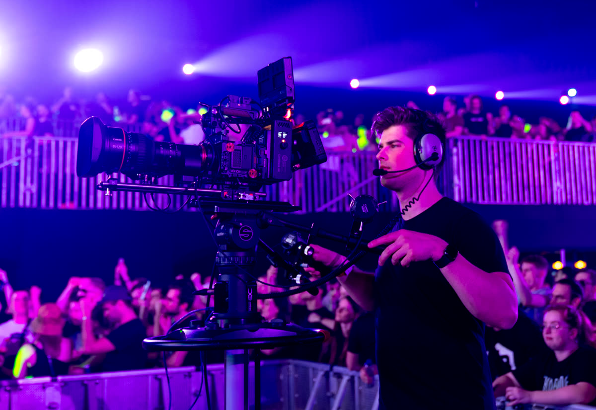 Live multicam operator with headset on a broadcast camera in a packed arena